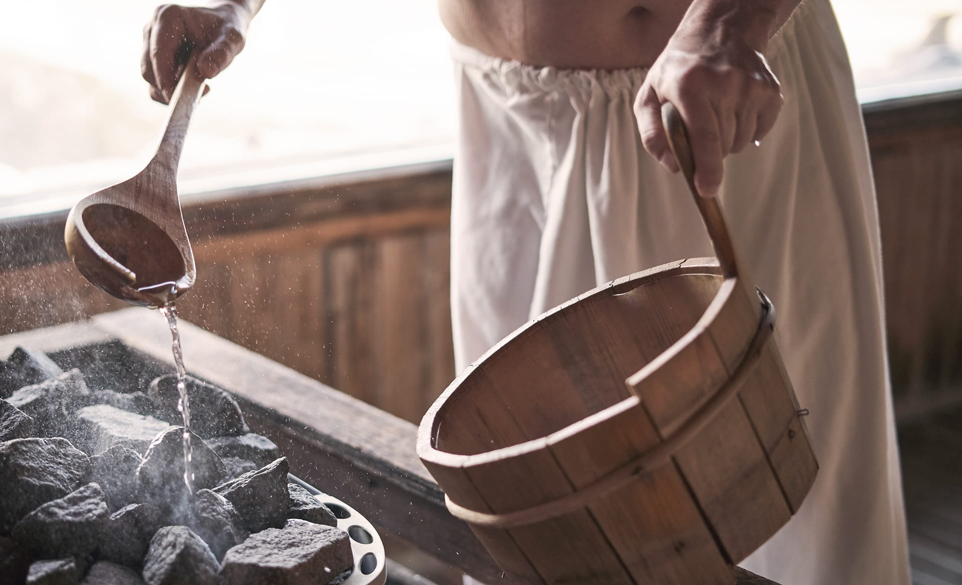 Man,Pouring,Water,Onto,Hot,Stone,In,Sauna,Room.,Steam